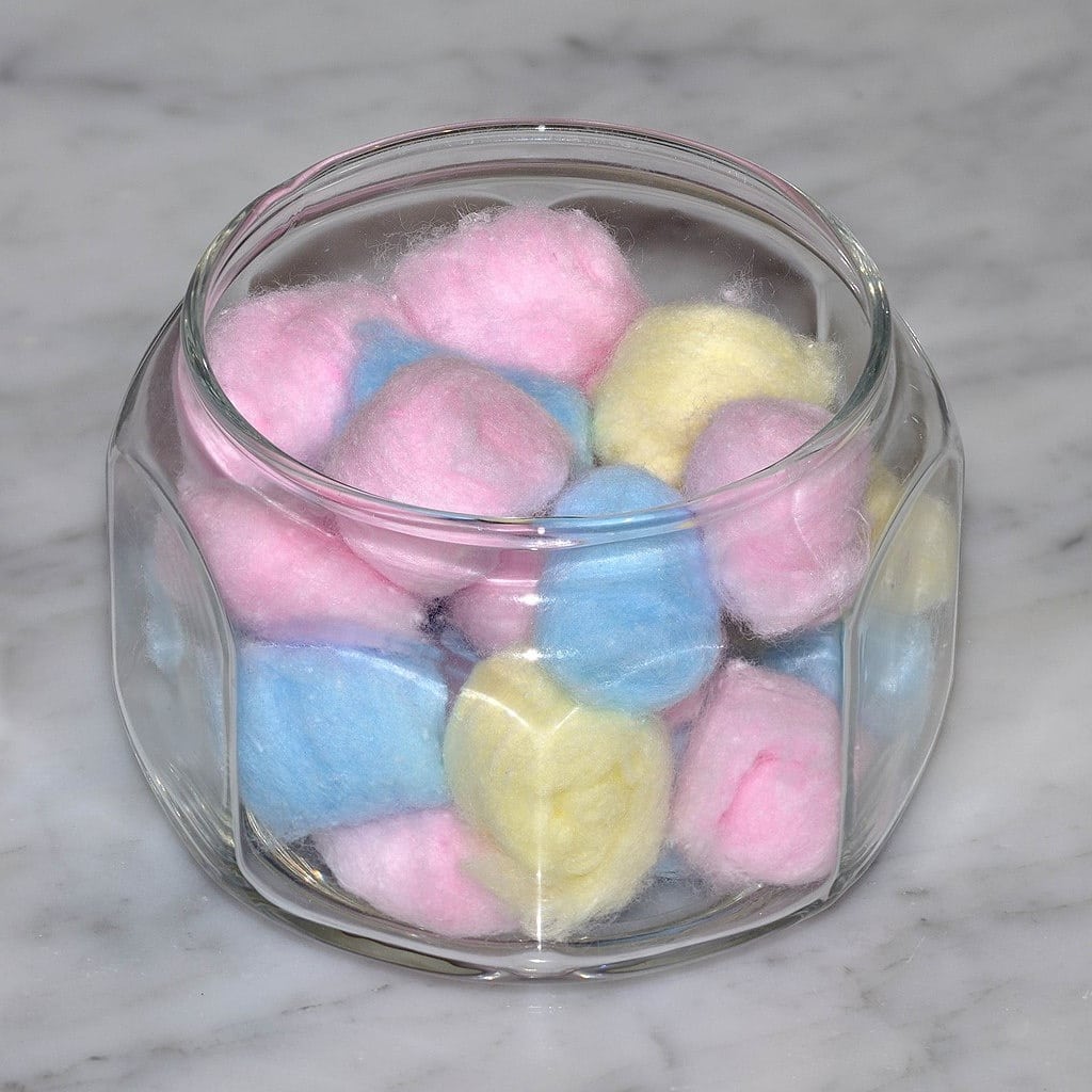 Blue, pink, and yellow colored cotton balls in jar