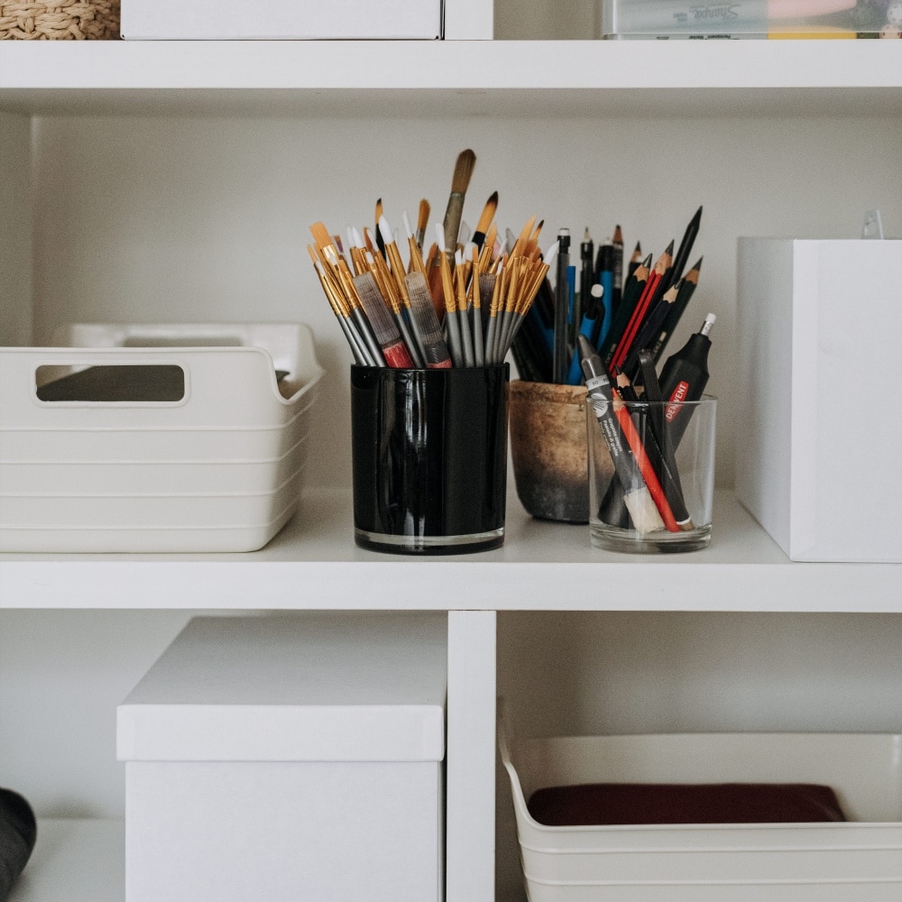 A shelf with storage bins and paintbrushes