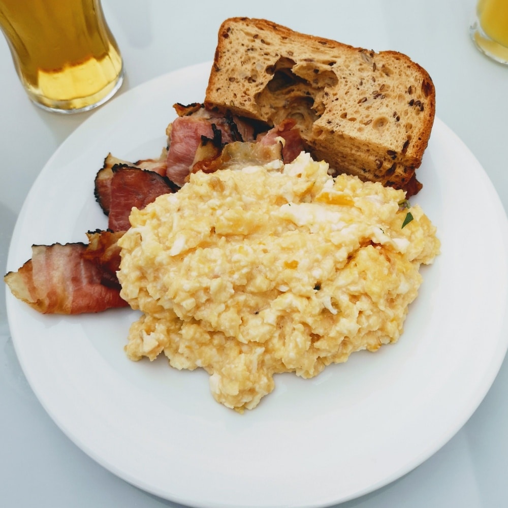 Soft scrambled egg, bacon, and toast on plate